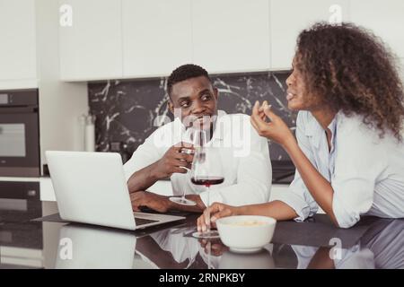 I neri sposano vino bevono datteri chiacchierando insieme rilassarsi incontrarsi in cucina, casa, colori vintage Foto Stock