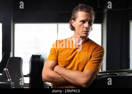 ritratto sport sano adulto europeo caucasico maschio modello in piedi sicuro braccio incrociato in palestra fitness Foto Stock