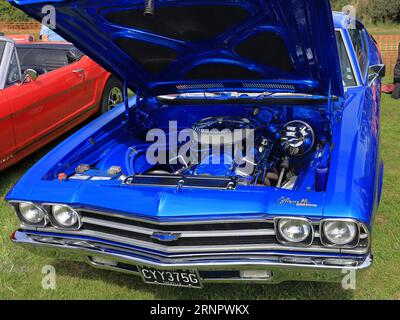 Sotto il cofano di una Chevrolet Chevelle blu del 1969 in mostra. Il Gosport Car Rally è organizzato dal Rotary Club locale e si svolge a Stokes Bay il lunedì festivo di agosto. L'evento di quest'anno, che offriva una giornata economica in famiglia, è stato il settantesimo e ha ospitato auto e moto d'epoca, un allevamento di animali domestici, bancarelle, rinfreschi e un'arena che ha fornito varie forme di intrattenimento. Foto Stock