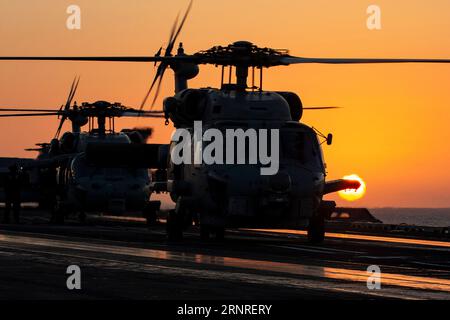 Mar Mediterraneo, acque internazionali. 30 agosto 2023. Un elicottero MH-60R Sea Hawk della Marina degli Stati Uniti, sagomato dal tramonto, si prepara al decollo dal ponte di volo a bordo della portaerei classe Nimitz USS Gerald R. Ford operante sul Mar Mediterraneo orientale, il 30 agosto 2023 al largo della costa greca. Credito: MC2 Nolan Pennington/U.S. Navy Photo/Alamy Live News Foto Stock