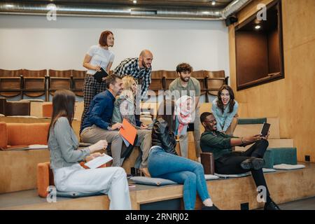 Persone d'affari positive sorridono allegramente durante una riunione in un'aula universitaria. Gruppo di professionisti aziendali di successo che lavorano come team in un Foto Stock