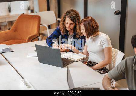 Ragazza che punta al telefono. Sta mostrando qualcosa al suo collega di sesso maschile Foto Stock