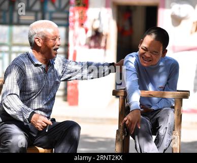 (171027) -- NANCHANG, 27 ottobre 2017 -- Zhong Ruijin (L) e Zhong Jiagu siedono al sole nel villaggio di Liantang della contea di Huichang, provincia orientale dello Jiangxi della Cina, 26 ottobre 2017. Zhong Jiagu fu abbandonato dai suoi genitori impoveriti 30 anni fa, quando nacque con rachitismo congenito incurabile. Fortunatamente per il neonato, è stato adottato dal villaggio Zhong Ruijin come nipote di Zhong. L'uomo dal cuore gentile si è preso cura di suo nipote negli ultimi 30 anni. Si tengono a vicenda, e non si pentono mai.) (wf) CHINA-JIANGXI-ADOPTION-DAILY LIFE (CN) HuxChenhuan PUBLICATIONxNOTxINxCHN Foto Stock