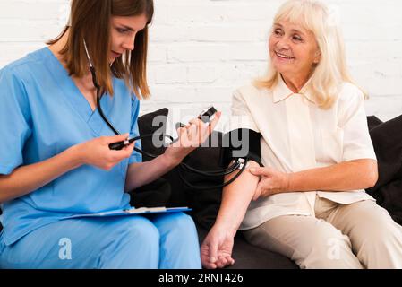 Controllo della pressione arteriosa della donna anziana in vista frontale Foto Stock