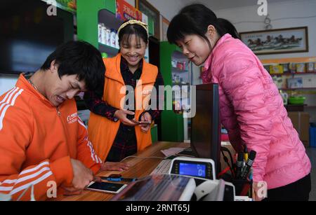 (171031) -- SHUCHENG, 31 ottobre 2017 -- Huang Bin (L) ripara il telefono cellulare per l'abitante Huang Yan (R) nel villaggio Shuhe della contea di Shucheng, provincia di Anhui della Cina orientale, 30 ottobre 2017. Il giovane di 29 anni Huang Bin con paralisi cerebrale gestì una mensa dopo essersi diplomato alla scuola media. Nel 2010 ha aperto un negozio di abbigliamento on-line e nel frattempo ha lavorato part-time per altri negozi on-line. Tre anni dopo, Huang Bin incontrò sua moglie He Linqiong, una ragazza del Sichuan della Cina sud-occidentale, attraverso lo shopping online. Nel 2015, Huang è diventato partner della piattaforma di vendita online Taobao con l'aiuto di o Foto Stock