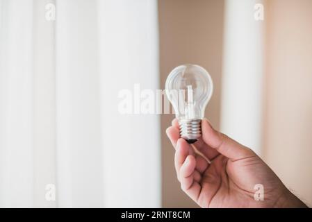 Primo piano con la mano dell'uomo che tiene una lampadina trasparente Foto Stock