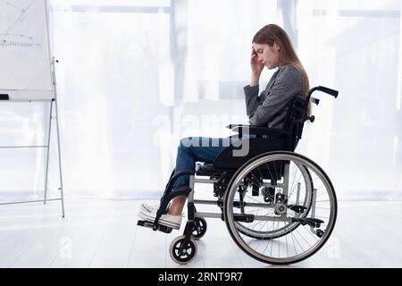 Full shot donna triste sedia a rotelle Foto Stock