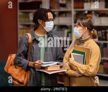 Studenti che indossano maschere mediche biblioteca Foto Stock