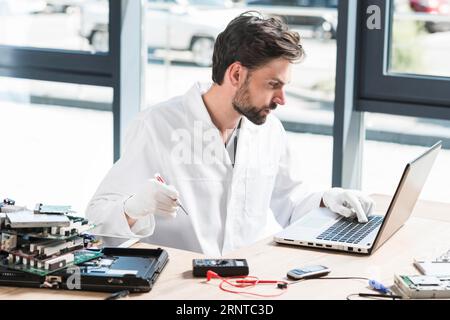 Un giovane tecnico maschio che utilizza un'officina per computer portatili Foto Stock