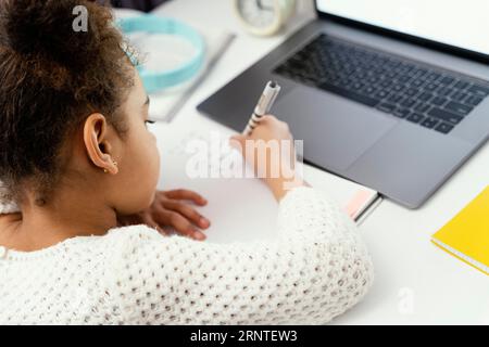 Bambina che frequenta la scuola online a casa usando un notebook Foto Stock