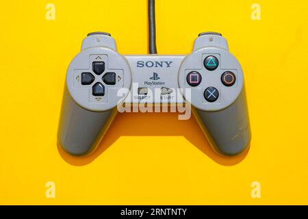 Controller Sony PlayStation 1 originale, vista dall'alto su sfondo giallo Foto Stock