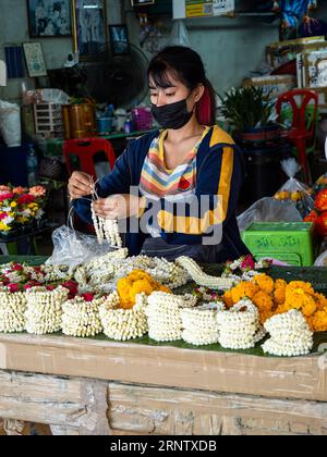 I fiori si trasformano in Phuang Malai, le splendide ghirlande della cultura tailandese, sotto le dita agili di un creatore di Bangkok. Foto Stock