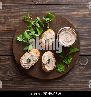 Toasted bread with chicken liver pate on cutting board over wooden background. Top view, flat lay Stock Photo