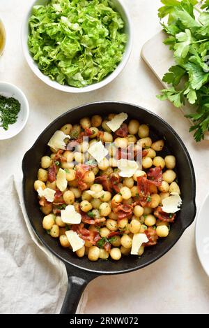 Gnocchi di patate con pancetta e parmigiano in teglia di ghisa su sfondo leggero. Vista dall'alto, base piatta Foto Stock