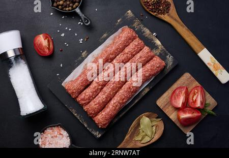 Salsicce crude al kebab di lula su tavola e spezie, vista dall'alto Foto Stock