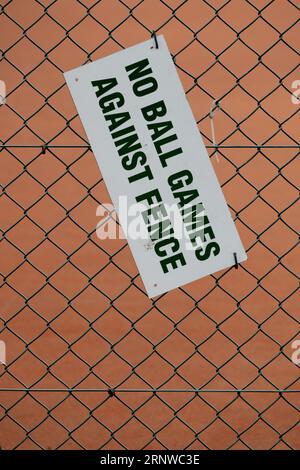 Cartello "no ball games against fence" sulla recinzione con maglie a catena Foto Stock