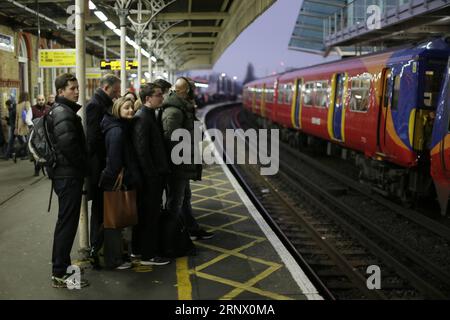 (180108) -- LONDRA, 8 gennaio 2018 -- i pendolari attendono su una banchina alla stazione di Clapham Junction come membri del sindacato Rail, Maritime and Transport (RMT) tengono cartelli alla stazione di Waterloo come Northern, Merseyrail, i lavoratori della South Western Railway e della Greater Anglia scioperarono su questioni separate tra cui il ruolo delle guardie ferroviarie e l'estensione dei servizi riservati ai conducenti, a Londra, in Gran Bretagna, l'8 gennaio 2018. ) (zf) REGNO UNITO-LONDRA-SCIOPERO FERROVIARIO TimxIrlanda PUBLICATIONxNOTxINxCHN Foto Stock