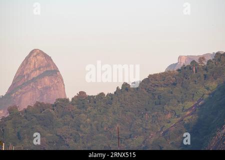 Rio de Janeiro, Brasile: Skyline con luce rosa dell'alba, montagne e vegetazione verde, vegetazione lussureggiante e foresta pluviale nel centro della città Foto Stock