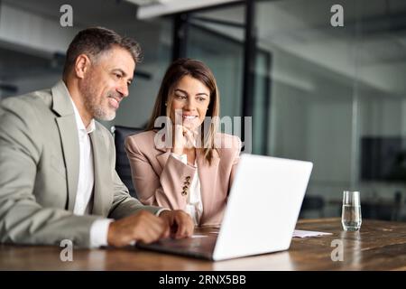 Due dirigenti aziendali professionali che lavorano su un computer portatile durante una riunione d'ufficio. Foto Stock