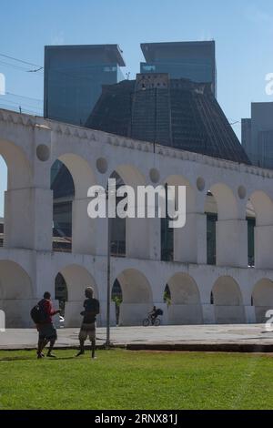 Rio de Janeiro, Brasile: Persone di fronte all'Acquedotto Carioca (Arcos da Lapa) con la Cattedrale metropolitana di San Sebastiano sullo sfondo Foto Stock