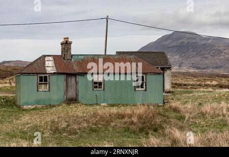 Vecchia casa fatta di fogli di ferro ondulati con pareti verdi e un tetto rosso nel mezzo del nulla Foto Stock