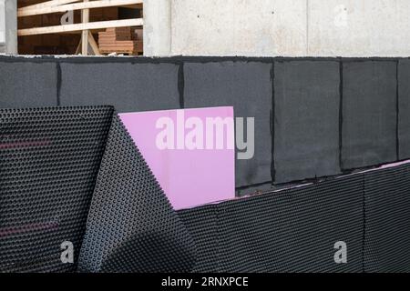 Rivestimenti impermeabili e di isolamento termico a terra applicati sulla parete inferiore della fondazione in una nuova casa in costruzione. Membrane in PVC per edilizia Foto Stock