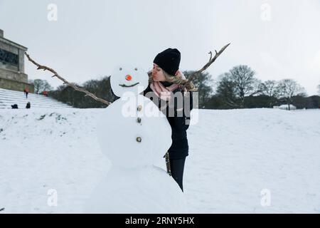 (180228) -- DUBLINO, 28 febbraio 2018 () -- Una donna si trova accanto a un pupazzo di neve a Phoenix Park a Dublino, Irlanda, 28 febbraio 2018. Una tempesta di neve ha colpito la maggior parte dell'Irlanda mercoledì, che è stata segnalata come la peggiore tempesta di neve in Irlanda dal 1982. () IRLANDA-DUBLINO-TEMPESTA DI NEVE Xinhua PUBLICATIONxNOTxINxCHN Foto Stock