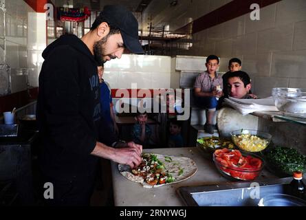 (180406) -- GHOUTA ORIENTALE, 6 aprile 2018 -- Un uomo siriano fa hummus e falafel nella città recentemente riconquistata di Ayn Tarma nella campagna orientale di Ghouta a Damasco, Siria, il 5 aprile 2018. L'ultima area detenuta dai ribelli nella capitale Damasco, la campagna di Ghouta orientale sta per cadere, con un nuovo accordo che vedrà l'evacuazione dei ribelli dell'esercito islamico verso la Siria settentrionale. (psw) SYRIA-DAMASCO-EASTERN GHOUTA-DAILY LIFE AmmarxSafarjalani PUBLICATIONxNOTxINxCHN Foto Stock