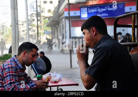 (180413) -- GHOUTA ORIENTALE (SIRIA), 13 aprile 2018 -- la gente mangia Shawarma nella città di Kafar Batna, Ghouta orientale, campagna di Damasco, Siria, il 13 aprile, 2018. l'esercito siriano ha riconquistato Kafar Batna e altre città della Ghouta orientale alla fine del mese scorso e le persone che hanno sofferto anni di assedio hanno iniziato a riprendersi la vita. ) SIRIA-DAMASCO-GHOUTA ORIENTALE-VITA QUOTIDIANA AMMARXSAFARJALANI PUBLICATIONXNOTXINXCHN Foto Stock