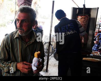 (180413) -- GHOUTA ORIENTALE (SIRIA), 13 aprile 2018 -- Un uomo mangia Shawarma nella città di Kafar Batna, Ghouta orientale, campagna di Damasco, Siria, il 13 aprile, 2018. l'esercito siriano ha riconquistato Kafar Batna e altre città della Ghouta orientale alla fine del mese scorso e le persone che hanno sofferto anni di assedio hanno iniziato a riprendersi la vita. ) SIRIA-DAMASCO-GHOUTA ORIENTALE-VITA QUOTIDIANA AMMARXSAFARJALANI PUBLICATIONXNOTXINXCHN Foto Stock