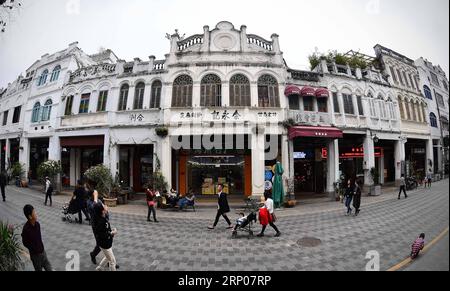 (180425) - HAIKOU, 25 aprile 2018 -- i turisti camminano sull'antica via Qilou ad Haikou, capitale della provincia di Hainan della Cina meridionale, 2 gennaio 2017. Gli edifici Qilou in stile Nanyang sono edifici affittuari di tipo balcone per uso sia residenziale che commerciale. Il primo piano di una casa Qilou è usato come negozio, e parte del secondo piano è appeso al primo piano ed è sostenuto da colonne, formando un riparo di fronte al negozio. La gente vive ai piani superiori. Le case di Qilou si allineano per formare una strada dello shopping, lasciando strapiombi su entrambi i lati della strada per proteggere i pedoni. )(wsw)(zt) CHINA-hai Foto Stock