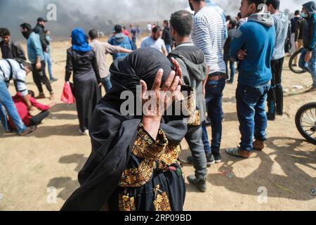 (180427) -- GAZA, 27 aprile 2018 -- Una donna palestinese copre il volto con le mani dal gas lacrimogeno sparato dalle truppe israeliane durante gli scontri a est della città di Gaza, il 27 aprile 2018. Stringer) MIDEAST-GAZA-CLASHES zhaoyue PUBLICATIONxNOTxINxCHN Foto Stock