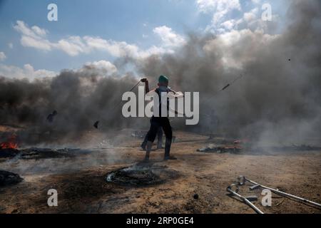 (180514) -- GAZA, 14 maggio 2018 -- Un manifestante palestinese usa una fionda per lanciare pietre contro le truppe israeliane durante gli scontri a Gaza, il 14 maggio 2018. ) (wtc) MIDEAST-GAZA-CLASH Stringer PUBLICATIONxNOTxINxCHN Foto Stock