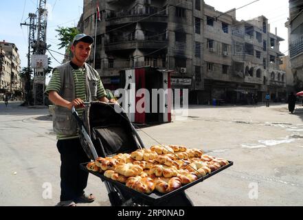 (180520) -- DAMASCO, 20 maggio 2018 -- Un venditore ambulante vende bagel su un passeggino nella campagna orientale di Ghouta, nella capitale Damasco, il 19 maggio 2018. Le persone nella zona di Ghouta orientale hanno iniziato a tornare alla vita normale e ad osservare le tradizioni del mese santo musulmano del Ramadan senza paura dopo che i ribelli sono stati allontanati da quella zona il mese scorso.) (yy) SIRIA-DAMASCO-GHOUTA EST-RAMADAN AmmarxSafarjalani PUBLICATIONxNOTxINxCHN Foto Stock