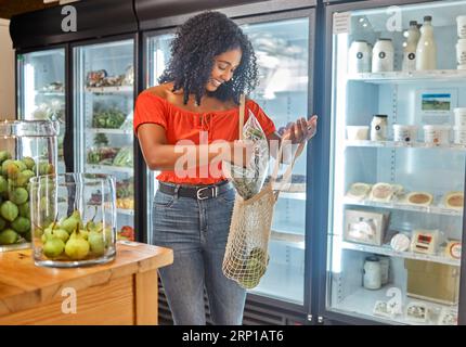 Donna, negozio e cliente con generi alimentari per borse, cibo e felice per lo shopping senza sprechi in un supermercato ecologico. Sostenibile, negozio al dettaglio e. Foto Stock