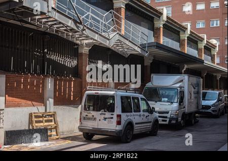 Un vicolo buio sul retro del mercato, furgoni e camion scaricati e parcheggiati Foto Stock