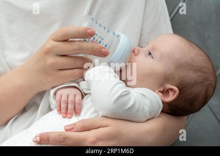 il bambino beve il latte da un biberon Foto Stock