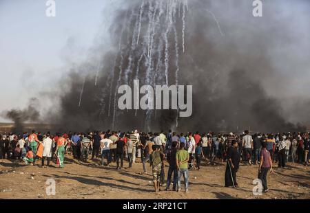 (180810) -- GAZA, 10 agosto 2018 -- i manifestanti palestinesi si riuniscono come una pioggia di bombole di gas lacrimogeni sparate dalle truppe israeliane atterrano sul campo durante gli scontri sul confine tra Gaza e Israele, a est della città di Gaza, il 10 agosto 2018. Due palestinesi, uno dei quali era medico, sono stati uccisi, e 307 palestinesi venerdì sono stati feriti in scontri vicino al confine tra Gaza e Israele, secondo il rapporto del Ministero della salute di Gaza. ) MIDEAST-GAZA-CLASH WissamxNassar PUBLICATIONxNOTxINxCHN Foto Stock