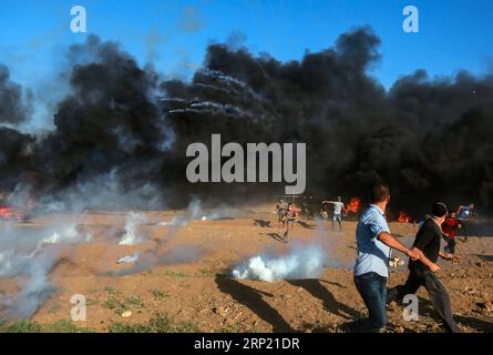 (180810) -- GAZA, 10 agosto 2018 () -- i manifestanti palestinesi corrono per coprire le bombole di gas lacrimogeni sparate dalle truppe israeliane durante gli scontri sul confine tra Gaza e Israele, a est della città di Gaza, il 10 agosto 2018. Due palestinesi, uno dei quali era medico, sono stati uccisi, e 307 palestinesi venerdì sono stati feriti negli scontri vicino al confine tra Gaza e Israele, secondo il rapporto del Ministero della salute di Gaza. () MIDEAST-GAZA-CLASHES Xinhua PUBLICATIONxNOTxINxCHN Foto Stock