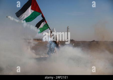 (180810) -- GAZA, 10 agosto 2018 () -- Un manifestante palestinese tiene bandiere durante gli scontri con le truppe israeliane sul confine tra Gaza e Israele, a est della città di Gaza, il 10 agosto 2018. Due palestinesi, uno dei quali era medico, sono stati uccisi, e 307 palestinesi venerdì sono stati feriti negli scontri vicino al confine tra Gaza e Israele, secondo il rapporto del Ministero della salute di Gaza. () MIDEAST-GAZA-CLASHES Xinhua PUBLICATIONxNOTxINxCHN Foto Stock