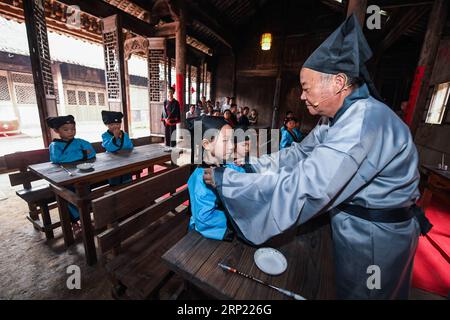 (180812) -- CHANGXING, 12 agosto 2018 (Xinhua) -- Un insegnante organizza vestiti per gli studenti in una vecchia scuola privata nel villaggio di Zhongshan nella contea di Changxing, nella provincia di Zhejiang nella Cina orientale, 12 agosto 2018. (Xinhua/Xu Yu) CHINA-ZHEJIANG-CHANGXING-TRADITIONAL CLASS (CN) PUBLICATIONxNOTxINxCHN Foto Stock