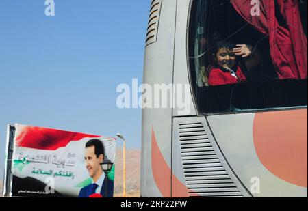 (180814) - DAMASCO, 14 agosto 2018 - Un ragazzo siriano agita la mano dall'interno di un autobus al confine tra Siria e Libano del 13 agosto 2018. Circa 150 rifugiati siriani sono tornati nel loro paese lunedì da Shabaa in Libano, hanno riferito i media locali. Questo è il quarto gruppo di rifugiati siriani che ritornano nella loro patria da Shabaa. )(gj) SIRIA-DAMASCO-RIFUGIATI-RITORNO-DAL-LIBANO AmmarxSafarjalani PUBLICATIONxNOTxINxCHN Foto Stock