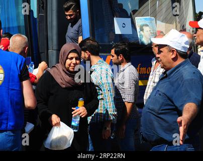 (180814) -- DAMASCO, 14 agosto 2018 -- i rifugiati siriani ricevono acqua e succhi di frutta dopo lo sbarco da un autobus che li ha trasportati dal Libano alla Siria al confine tra Siria e Libano, il 13 agosto 2018. Circa 150 rifugiati siriani sono tornati nel loro paese lunedì da Shabaa in Libano, hanno riferito i media locali. Questo è il quarto gruppo di rifugiati siriani che ritornano nella loro patria da Shabaa. )(gj) SIRIA-DAMASCO-RIFUGIATI-RITORNO-DAL-LIBANO AmmarxSafarjalani PUBLICATIONxNOTxINxCHN Foto Stock