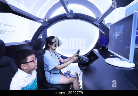 (180823) -- CHONGQING, 23 agosto 2018 -- la gente prova un simulatore di guida senza equipaggio al primo Smart China Expo nel comune di Chongqing della Cina sud-occidentale, 23 agosto 2018. Con Smart Technology: Potenziare l'economia, arricchire la vita come tema principale, la prima Smart China Expo si svolge da giovedì a sabato, concentrandosi su nuovi prodotti, tecnologie e modalità nello sviluppo globale dei big data e dei settori intelligenti. L'expo dispone di cinque aree espositive con una superficie totale di 186.000 metri quadrati, che attirano più di 500 aziende nazionali e internazionali come espositori e più di 100 GU stranieri Foto Stock