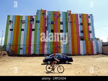 (180827) -- OUZAI, Aug. 27, 2018 -- Un ragazzo cavalca tra edifici con dipinti colorati a Ouzai, a sud di Beirut, Libano, il 26 agosto 2018. ) (Jmmn) LEBANON-OUZAI-BUILDINGS BilalxJawich PUBLICATIONxNOTxINxCHN Foto Stock