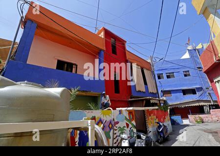 (180827) -- OUZAI, 27 agosto 2018 -- Un uomo si trova sul muro di un edificio con dipinti colorati a Ouzai, a sud di Beirut, Libano, il 26 agosto 2018. ) (Jmmn) LEBANON-OUZAI-BUILDINGS BilalxJawich PUBLICATIONxNOTxINxCHN Foto Stock