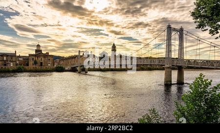 Passerella sospesa che passa sopra il fiume Ness nella splendida città di Inverness al tramonto, in Scozia. Foto Stock