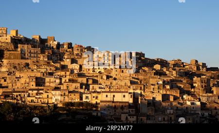 Luce notturna d'oro, case istroriche sul fianco della collina, Modica, città barocca, angolo barocco, sud-est, Sicilia, Italia Foto Stock