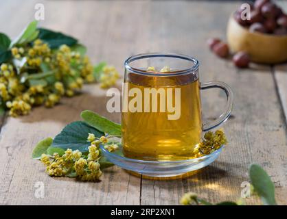 Fiori di lime freschi e tè al lime appena preparato sul tavolo. Concetto di tè aromatico e medicinale alle erbe Foto Stock