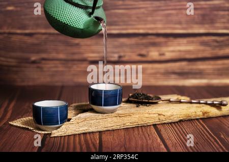 Una natura morta di piccole tazze di tè con un ruscello che cade dalla teiera Foto Stock